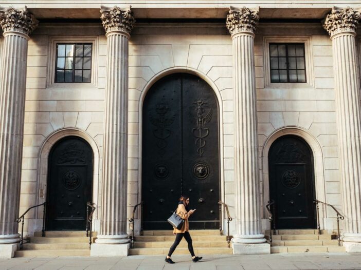 Woman walking in front of a bank style building