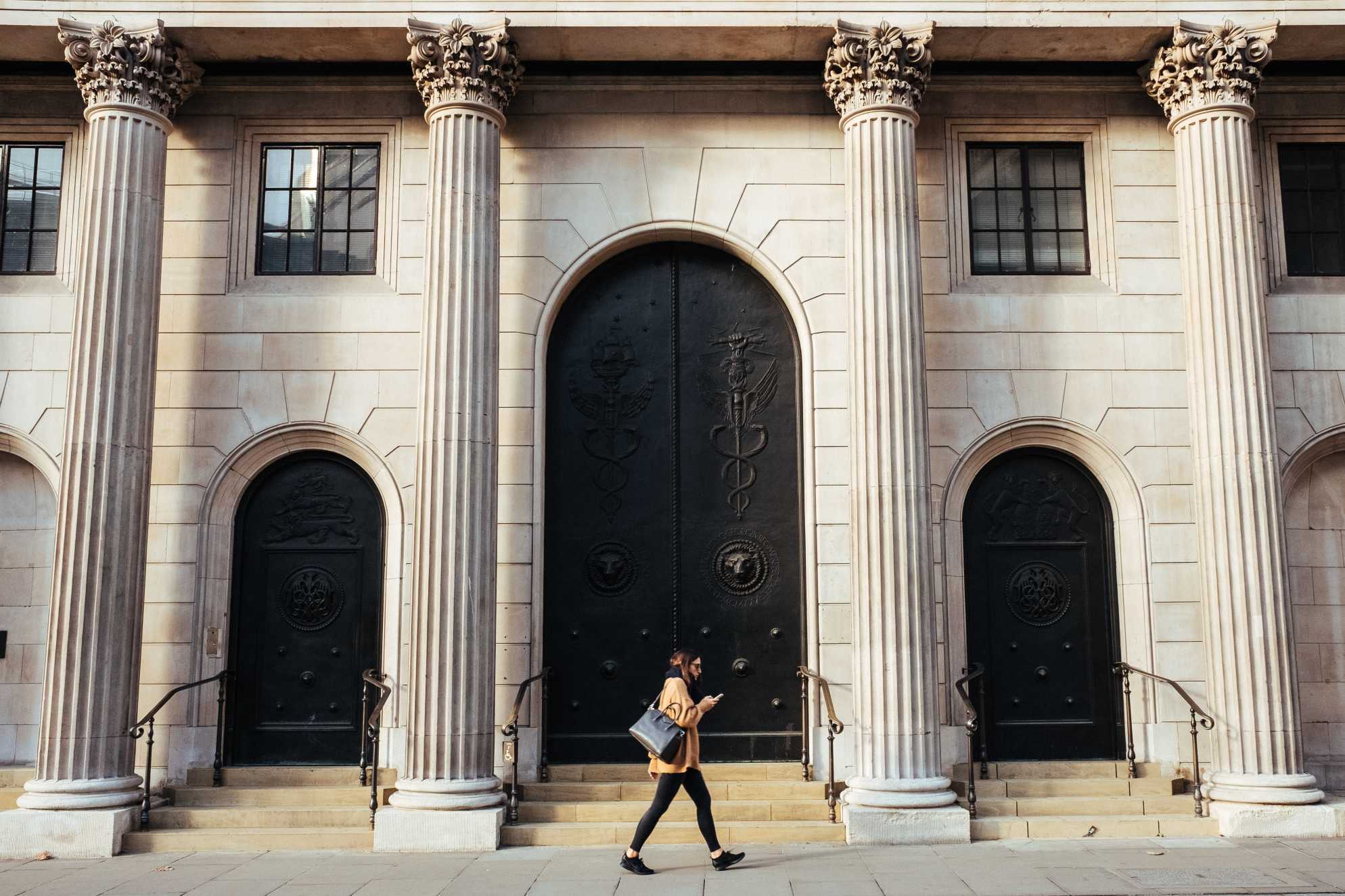 Woman walking in front of a bank style building